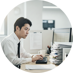 紙の申込書を見ながらシステムへ転記する担当者